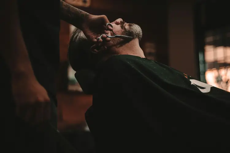 Photo of a barber trimming a client's beard.